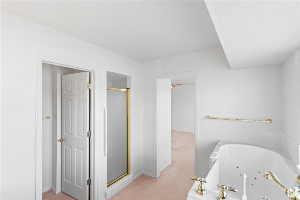 Bathroom featuring a tub with jets, a stall shower, and baseboards