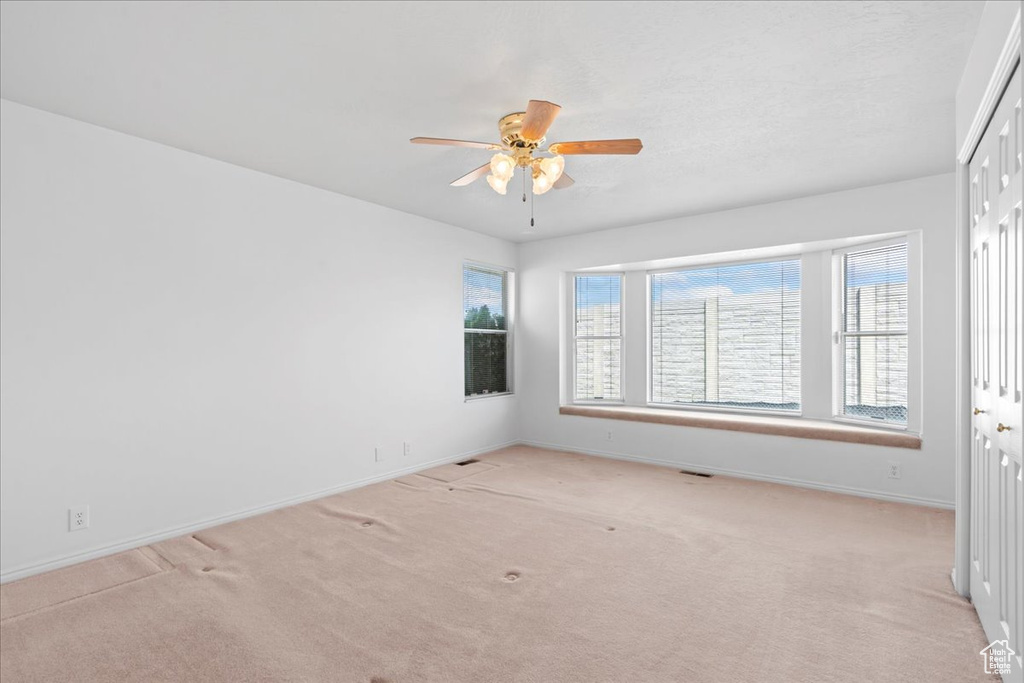 Spare room featuring baseboards, a ceiling fan, and light colored carpet