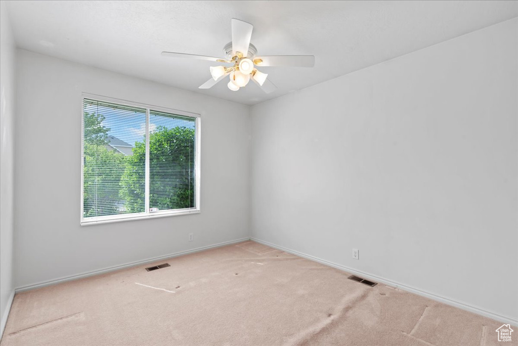 Carpeted spare room featuring a ceiling fan, visible vents, and baseboards