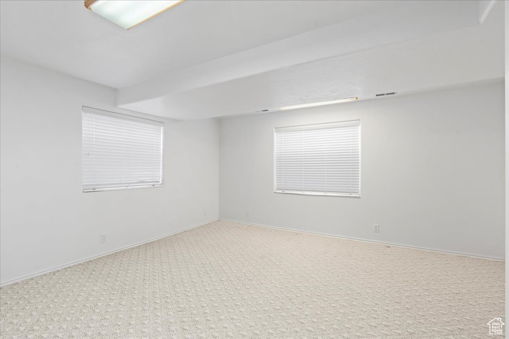 Spare room featuring visible vents, carpet, and baseboards