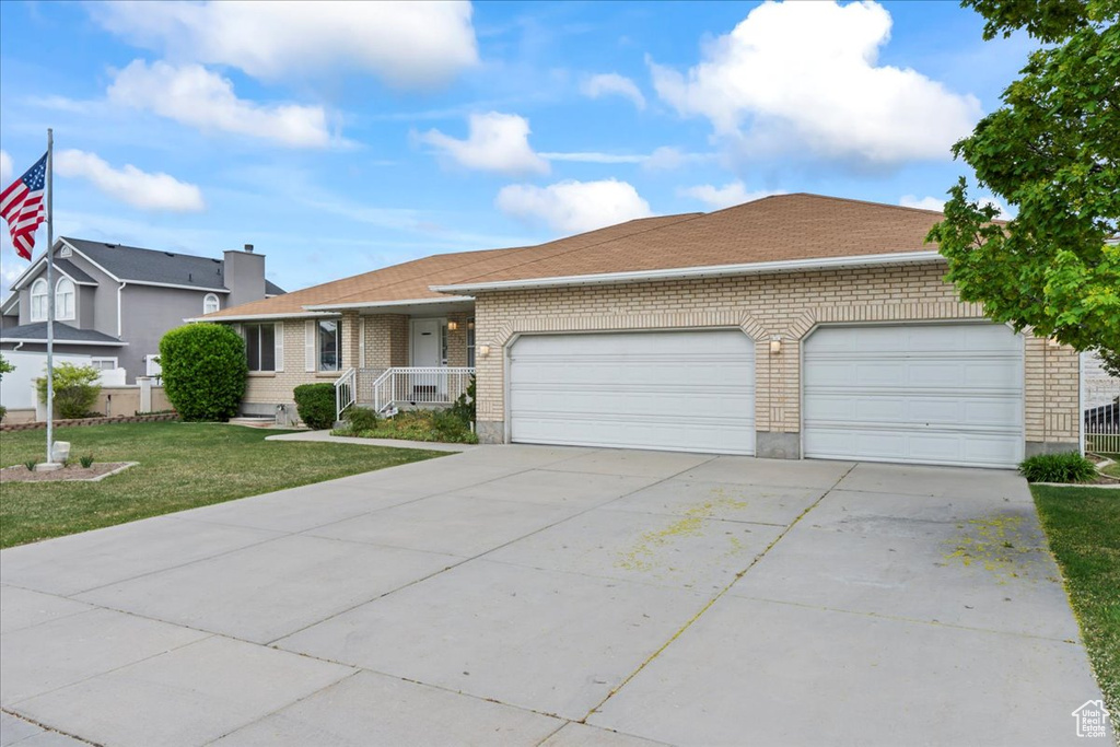 Single story home with a front lawn, a garage, a shingled roof, brick siding, and concrete driveway