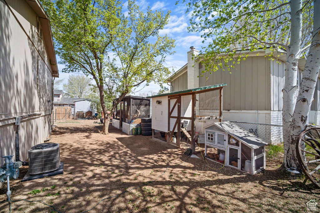View of yard with a fenced backyard, exterior structure, an outbuilding, and central AC unit