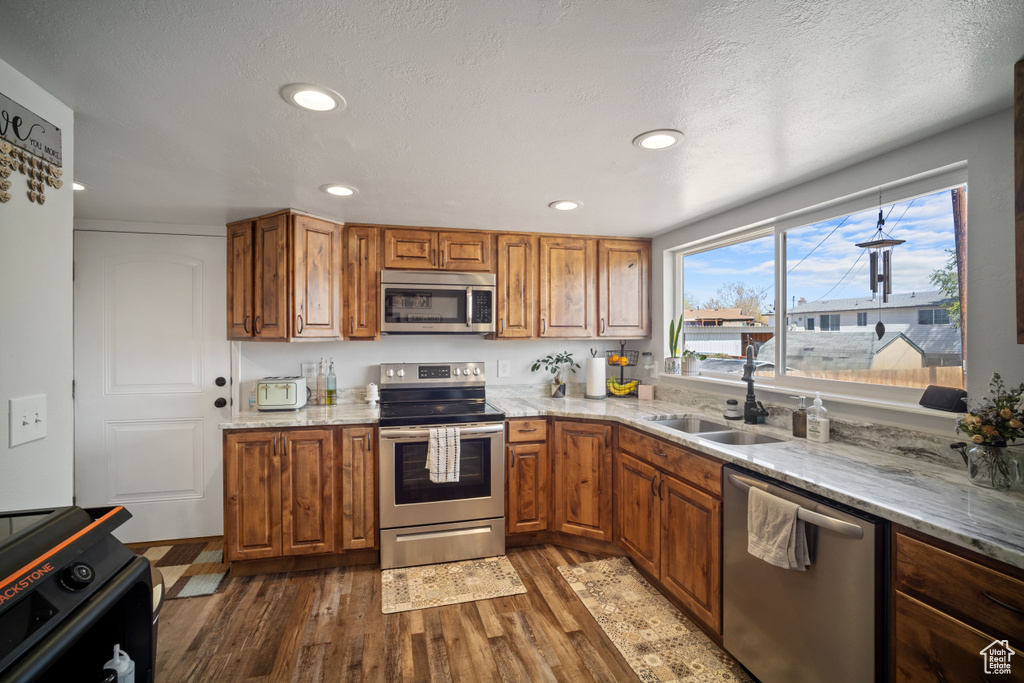 Kitchen featuring appliances with stainless steel finishes, dark wood-type flooring, and brown cabinets