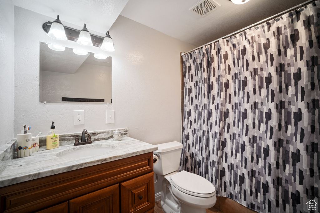 Bathroom featuring visible vents, toilet, curtained shower, and vanity