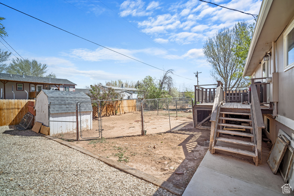 View of yard featuring a gate, a deck, a shed, and a fenced backyard