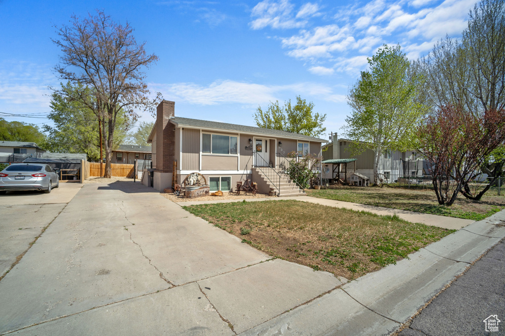View of front of home with driveway, fence, and a chimney