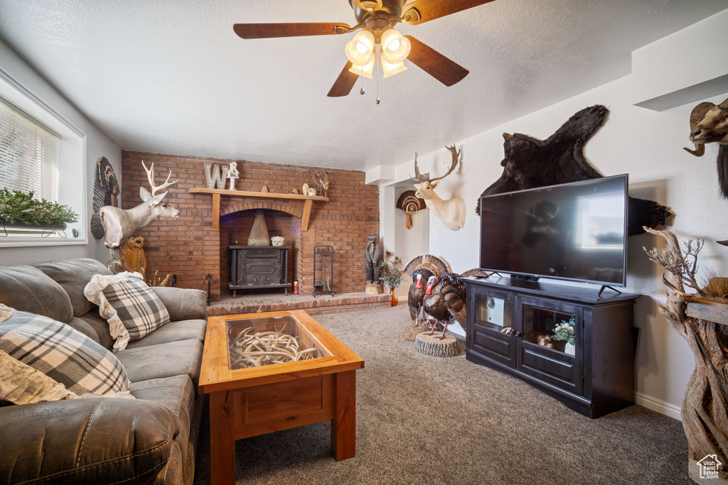 Living area featuring brick wall, a ceiling fan, carpet flooring, and a wood stove