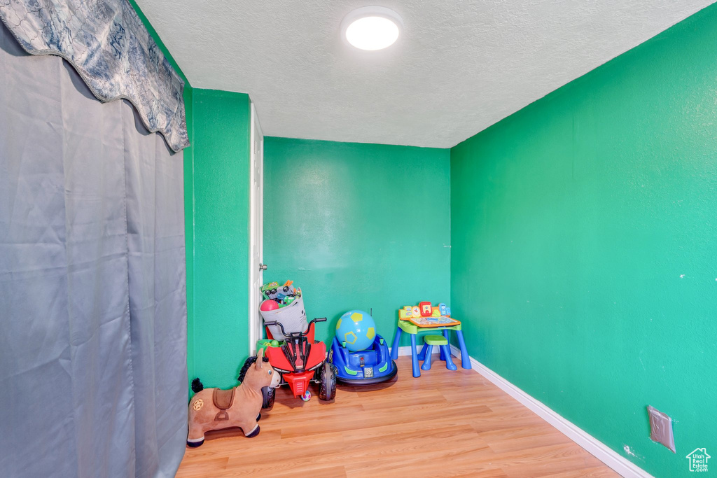 Playroom featuring a textured ceiling, wood finished floors, and baseboards