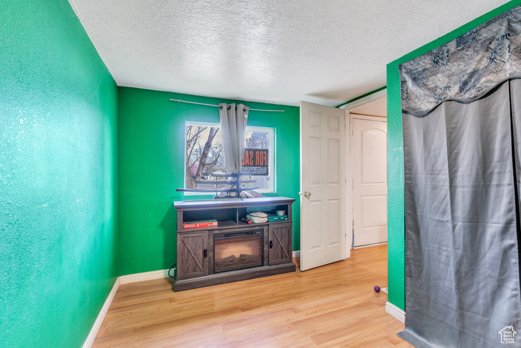 Interior space with a textured ceiling, wood finished floors, and baseboards