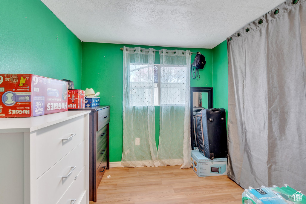 Miscellaneous room featuring a textured ceiling and light wood-type flooring