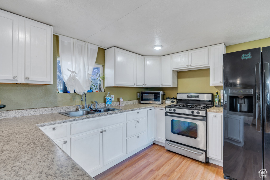Kitchen featuring white cabinets, light wood-style floors, appliances with stainless steel finishes, and a sink