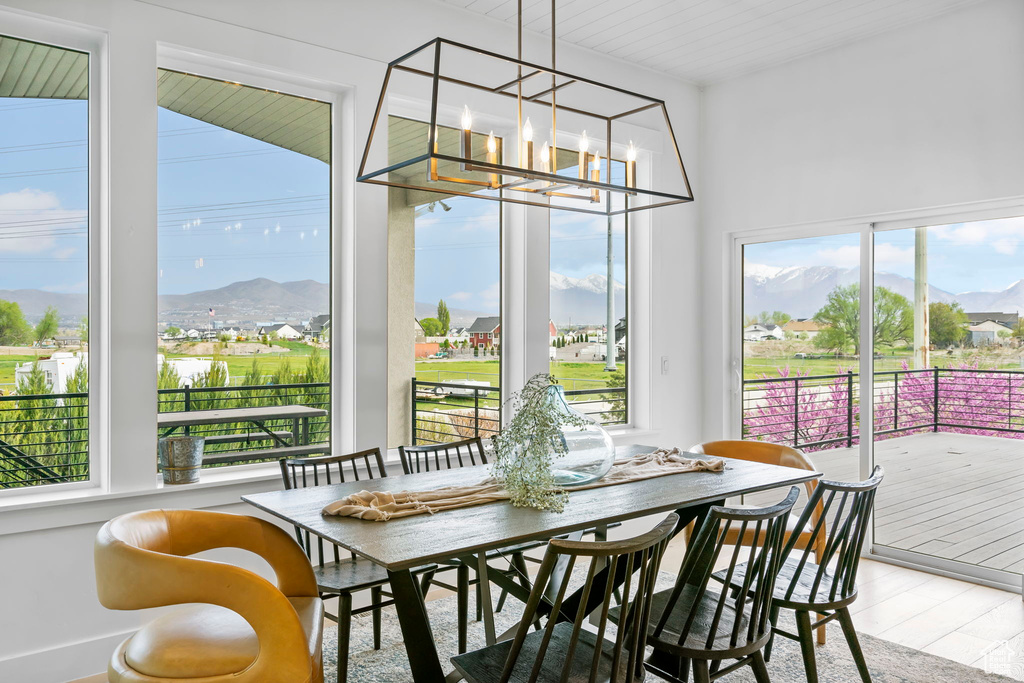 Interior space featuring wood finished floors, a chandelier, a healthy amount of sunlight, and a mountain view