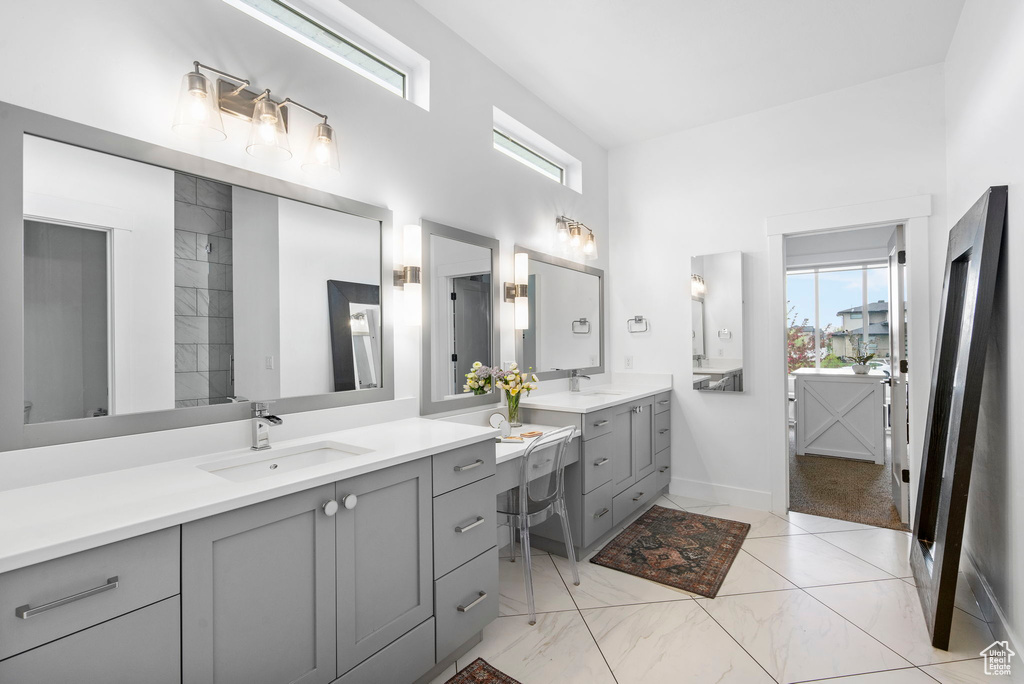 Full bathroom with baseboards, two vanities, a towering ceiling, and a sink