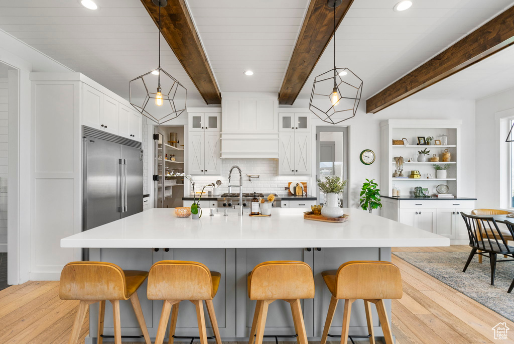 Kitchen featuring white cabinetry, open shelves, light wood-style flooring, and decorative backsplash