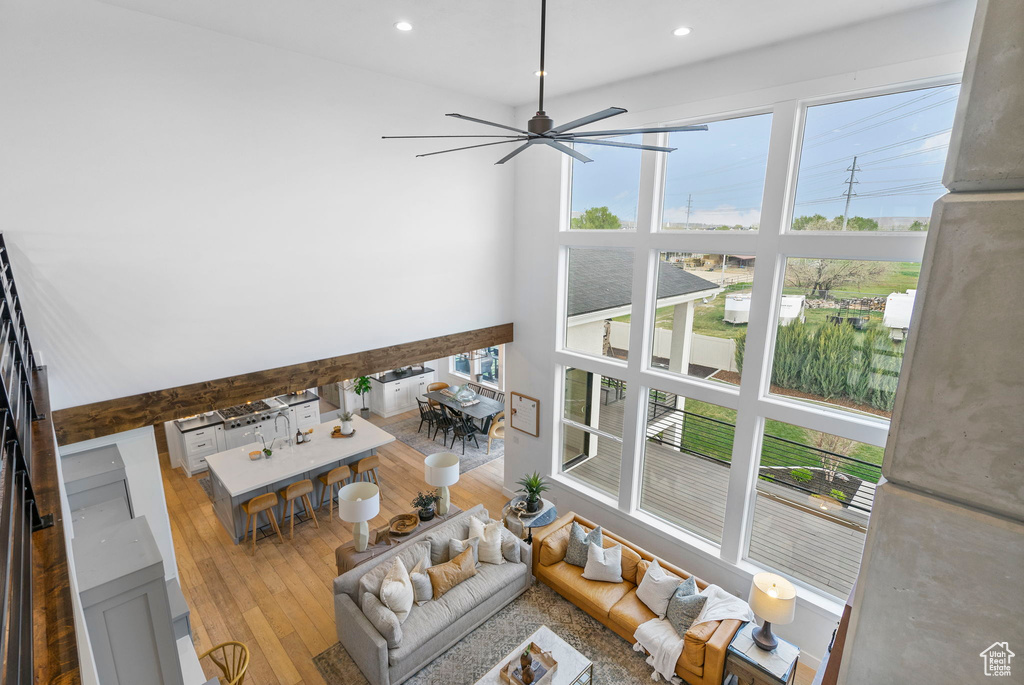 Living room featuring a high ceiling, recessed lighting, a ceiling fan, and hardwood / wood-style flooring