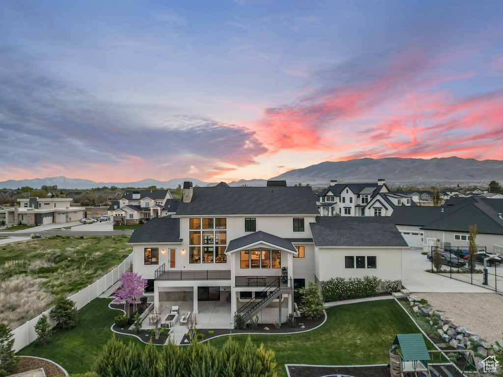 Rear view of house with stairway, a residential view, a yard, a fenced backyard, and a mountain view