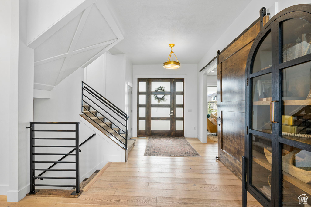 Entrance foyer featuring light wood finished floors, stairway, a barn door, baseboards, and french doors