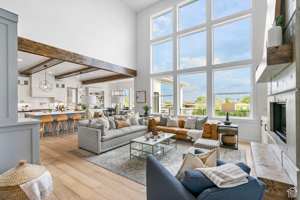 Living area with a premium fireplace, a healthy amount of sunlight, a high ceiling, and wood-type flooring