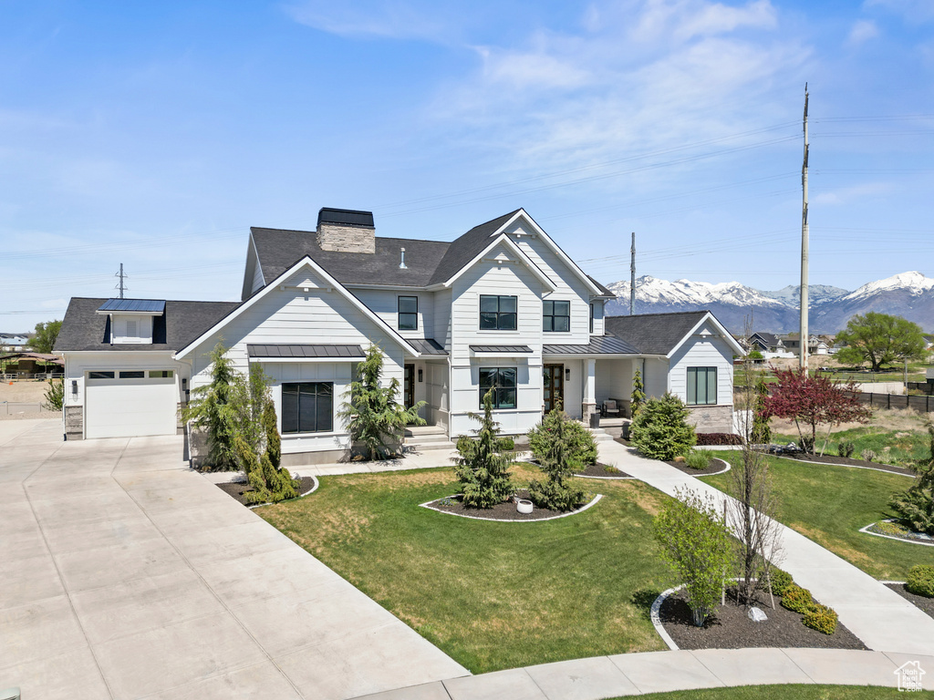 View of front facade with a chimney, a standing seam roof, metal roof, a garage, and concrete driveway