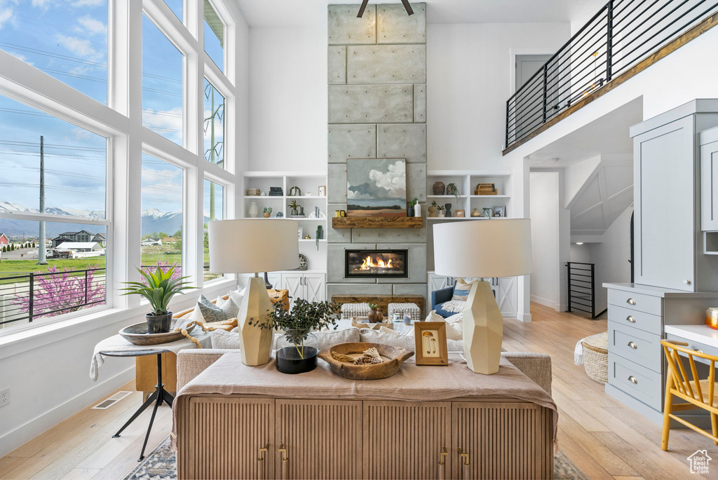 Living room featuring baseboards, light wood-style flooring, and a towering ceiling