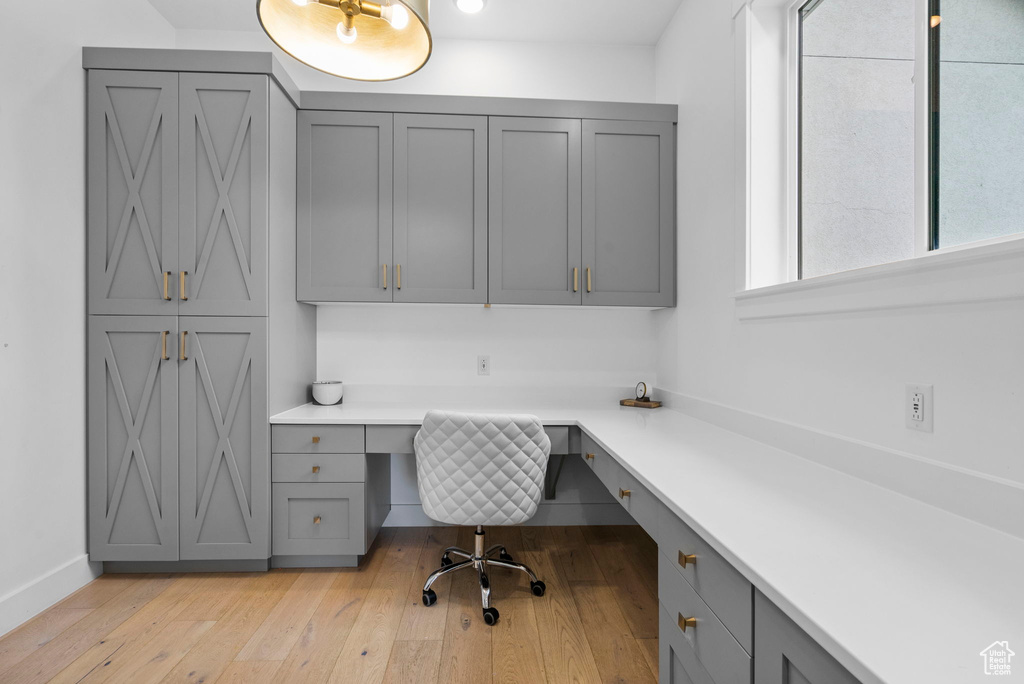 Office space featuring baseboards, light wood-type flooring, and built in study area