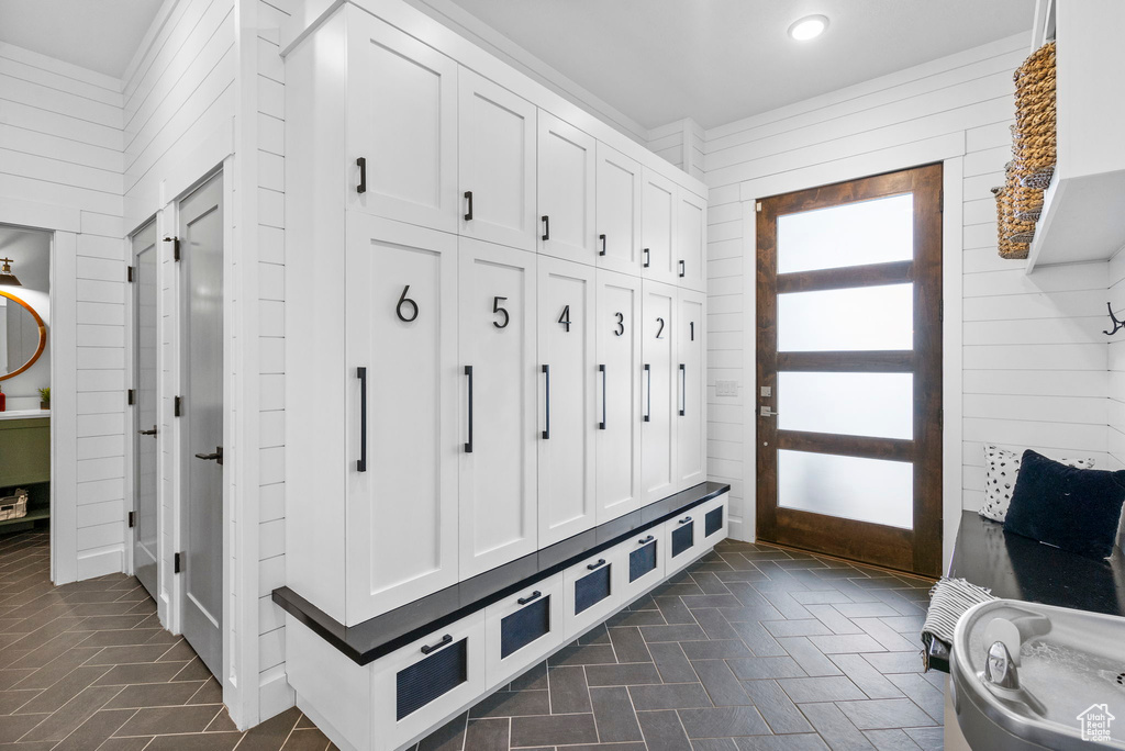 Mudroom featuring recessed lighting, brick floor, and wooden walls
