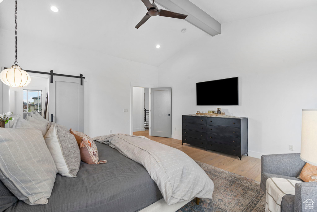 Bedroom with beamed ceiling, recessed lighting, a barn door, light wood-style floors, and high vaulted ceiling