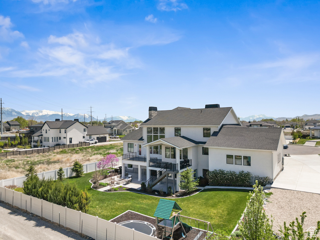 Back of property with a mountain view, a fenced backyard, a residential view, and stucco siding