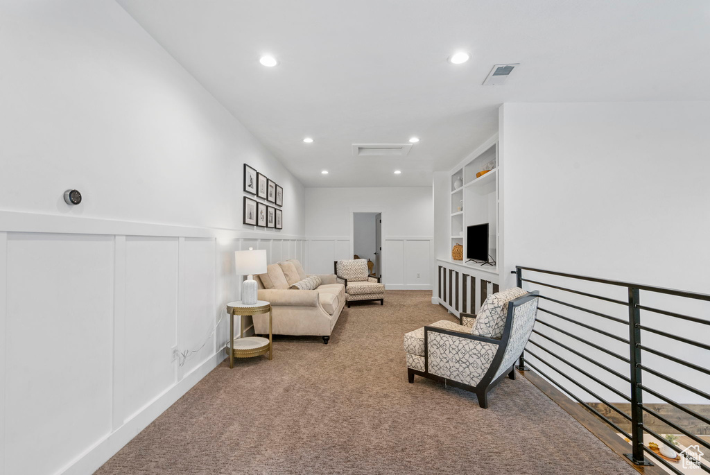 Carpeted living area with recessed lighting, a wainscoted wall, visible vents, and a decorative wall