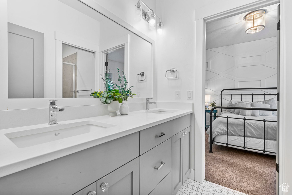 Full bathroom with double vanity, a shower stall, ensuite bathroom, and a sink