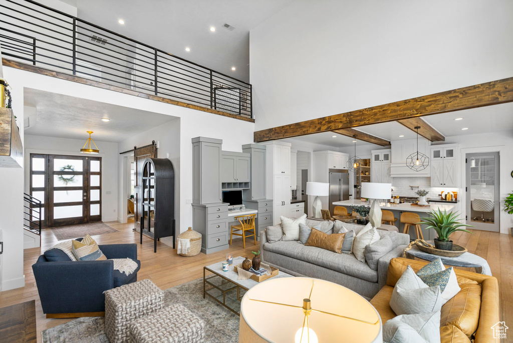 Living area with a high ceiling, a barn door, light wood-style floors, and recessed lighting