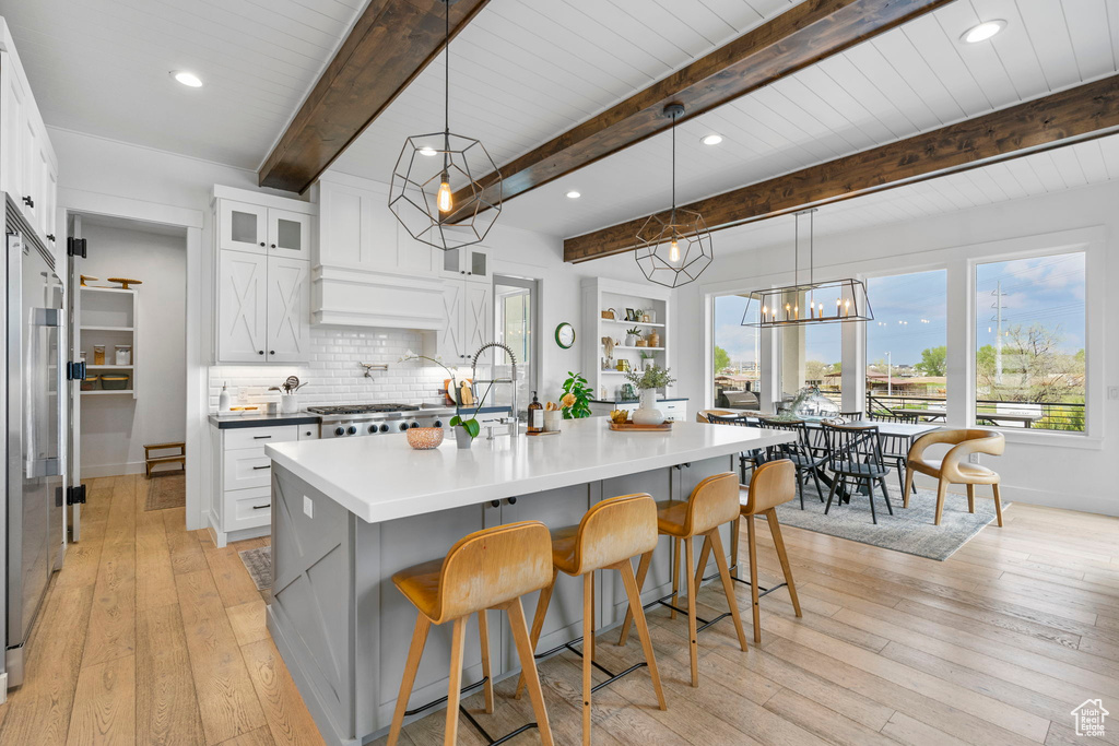 Kitchen with glass insert cabinets, a breakfast bar area, decorative backsplash, and light wood-style floors