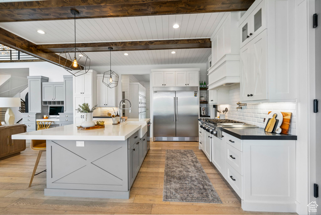 Kitchen with white cabinetry, tasteful backsplash, beamed ceiling, a sink, and appliances with stainless steel finishes