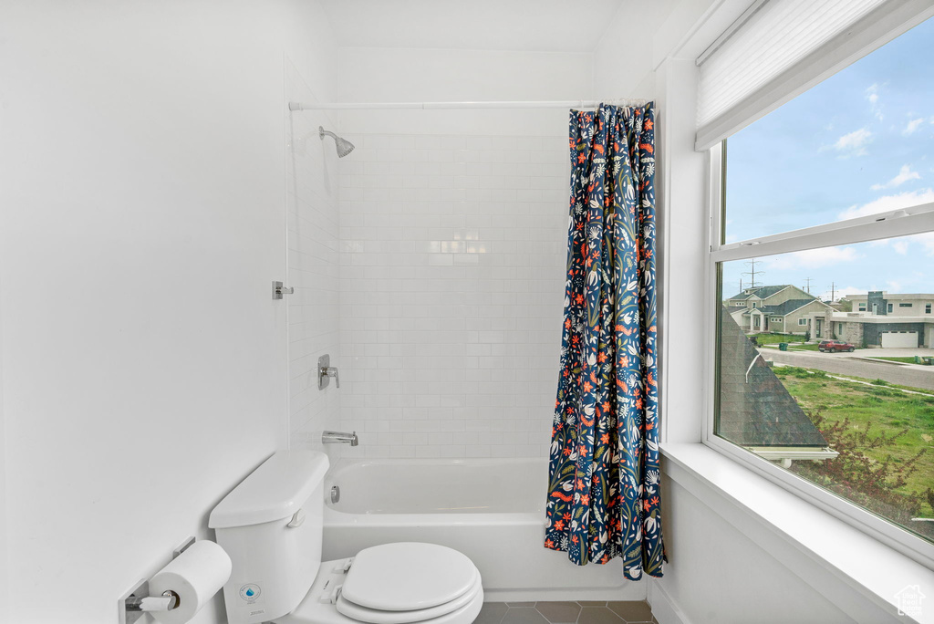 Bathroom featuring tile patterned floors, shower / bath combo, and toilet
