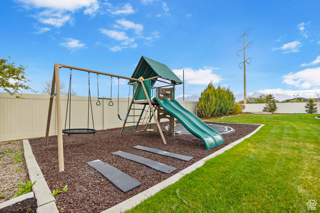 Community jungle gym with a fenced backyard and a lawn