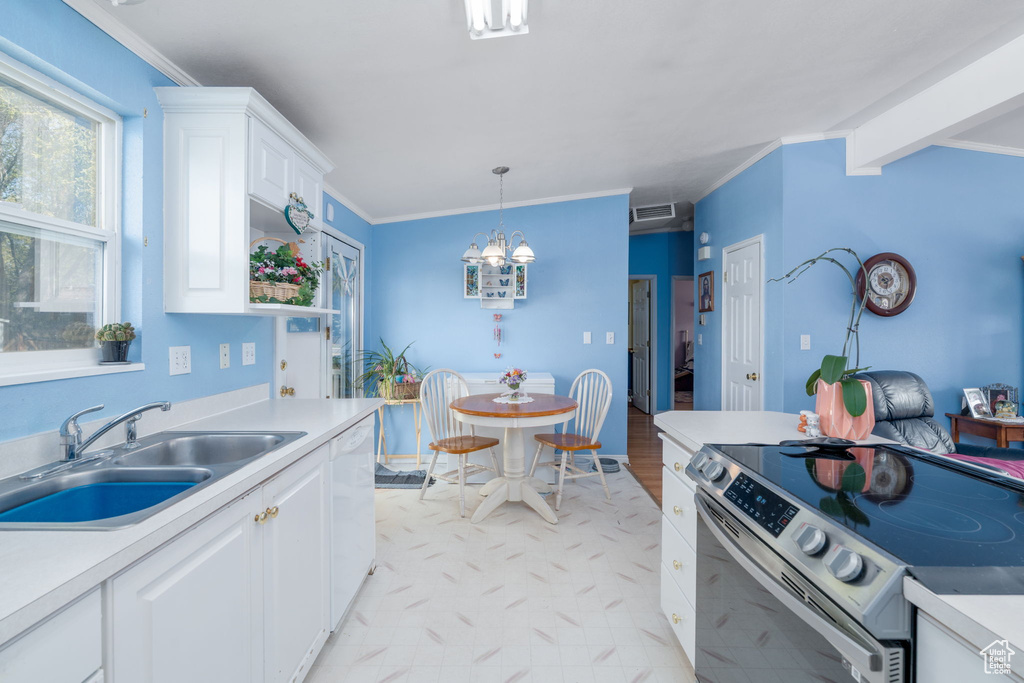 Kitchen with white cabinets, a sink, light countertops, electric range, and a notable chandelier