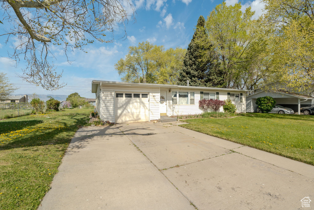 Single story home featuring driveway, a front lawn, and a garage