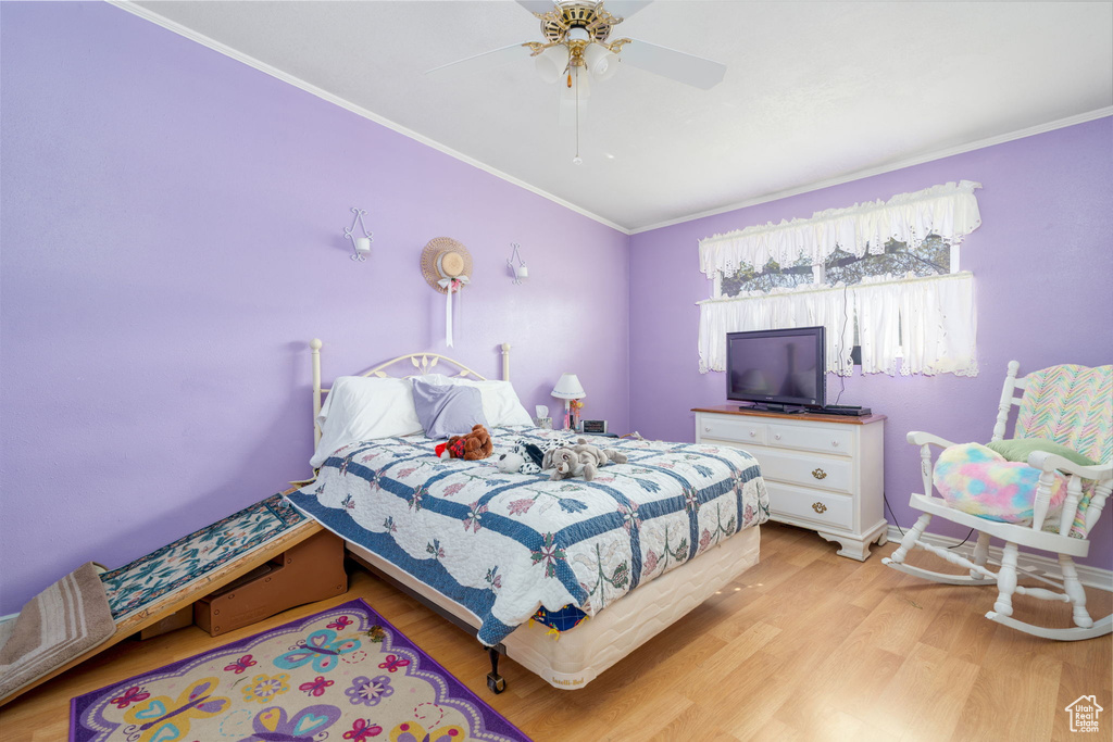 Bedroom with baseboards, light wood-type flooring, ceiling fan, and crown molding