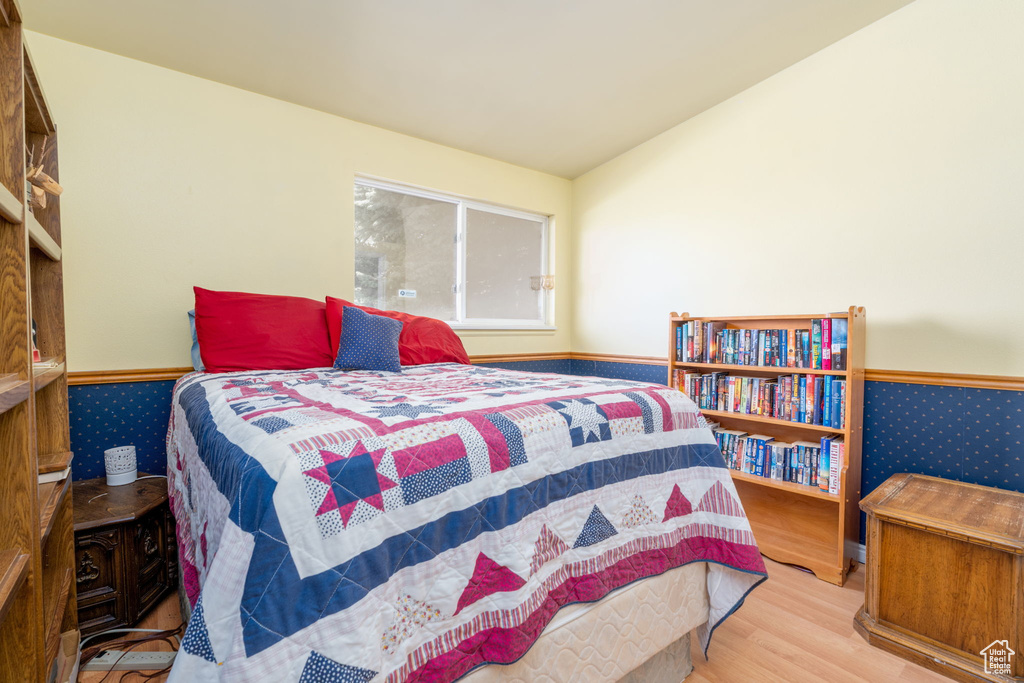 Bedroom with lofted ceiling, wainscoting, and wood finished floors
