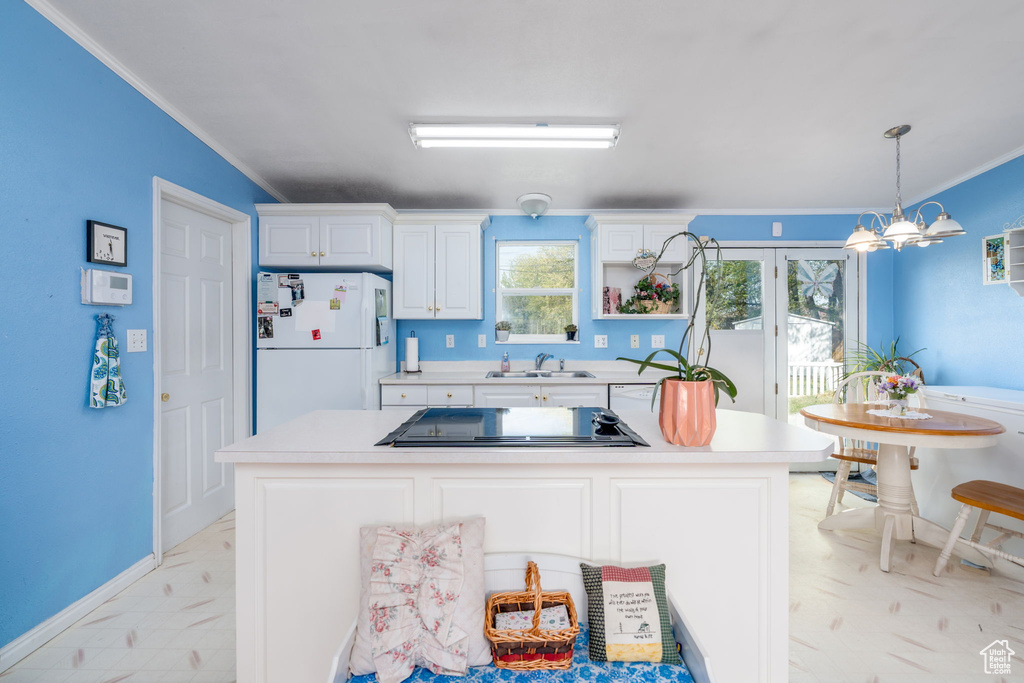 Kitchen featuring freestanding refrigerator, light countertops, black electric cooktop, a sink, and crown molding