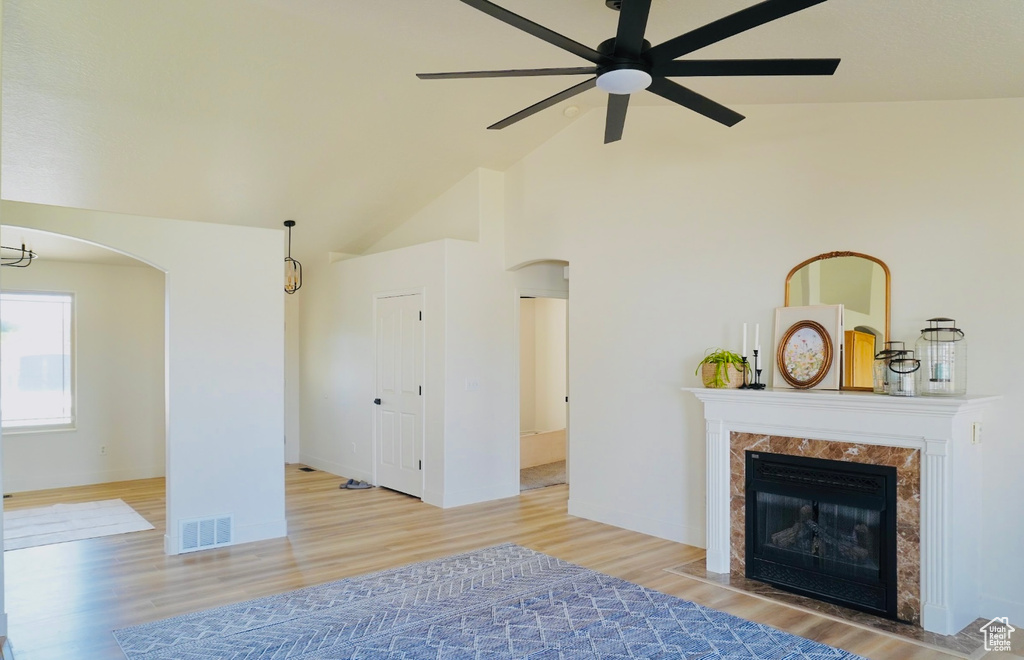 Living area with wood finished floors, arched walkways, ceiling fan, a premium fireplace, and visible vents
