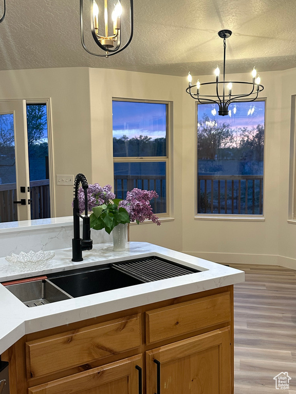 Kitchen featuring a chandelier, light wood-style floors, a textured ceiling, and a sink