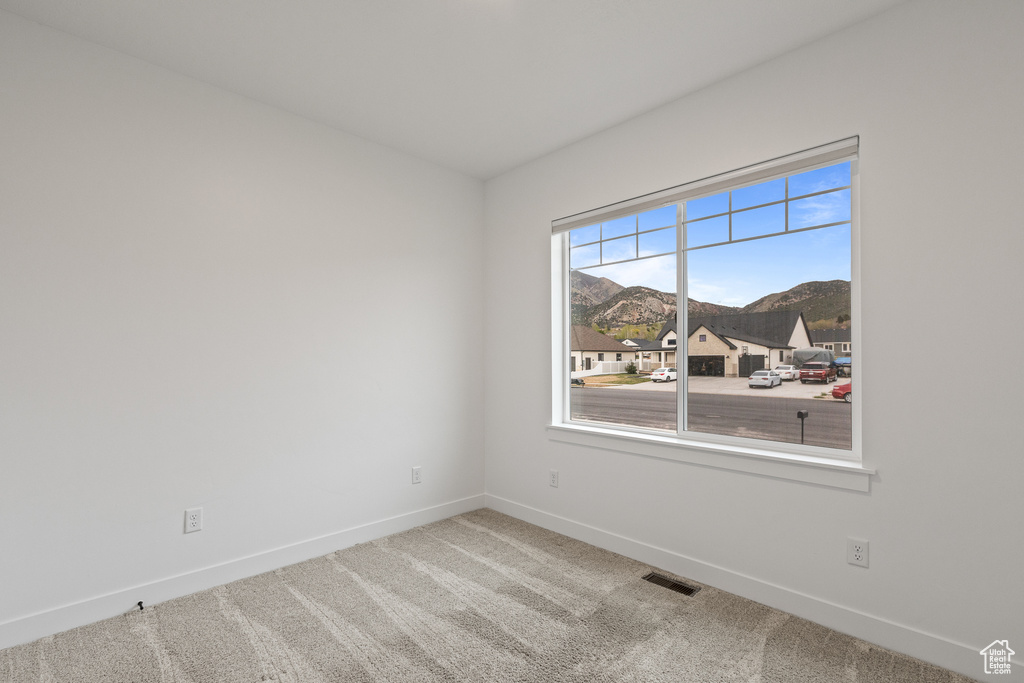 Carpeted empty room featuring a mountain view, visible vents, and baseboards