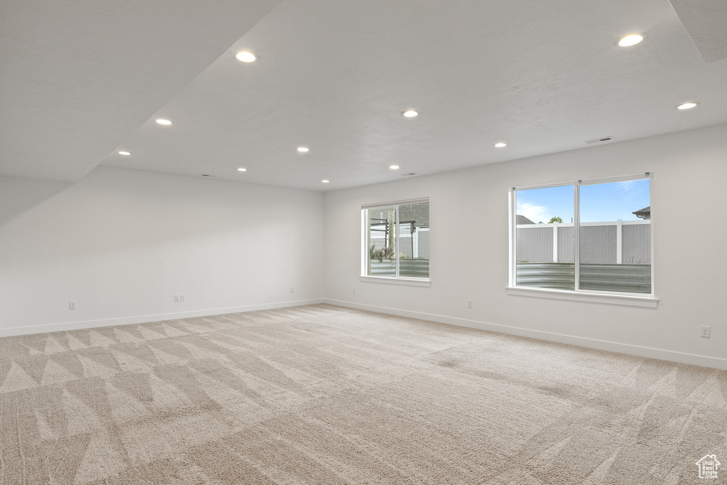 Empty room with baseboards, recessed lighting, and light carpet