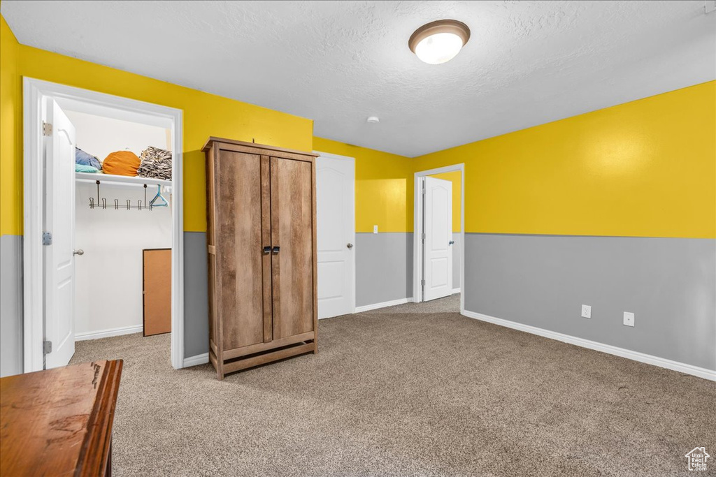 Unfurnished bedroom with a textured ceiling, baseboards, and carpet floors