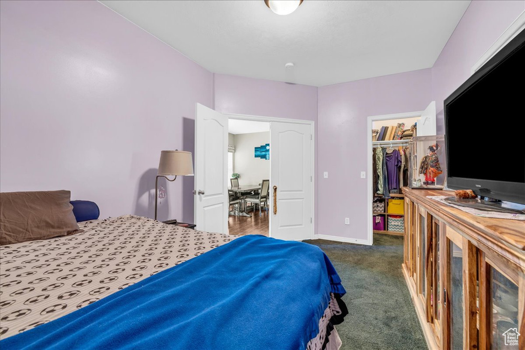 Bedroom with a spacious closet, a closet, carpet flooring, and baseboards