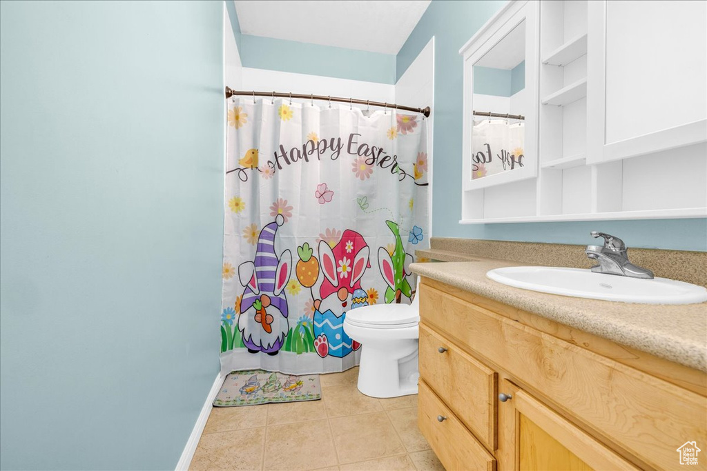Full bath featuring a shower with shower curtain, toilet, tile patterned flooring, and vanity