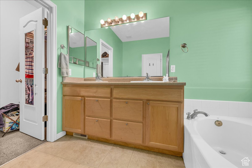 Full bath with tile patterned flooring, a bath, double vanity, and a sink