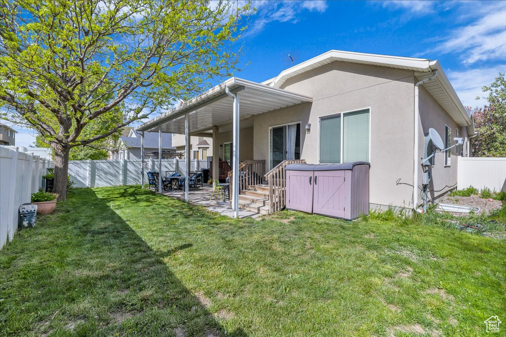 Rear view of house with a patio, a fenced backyard, stucco siding, and a yard