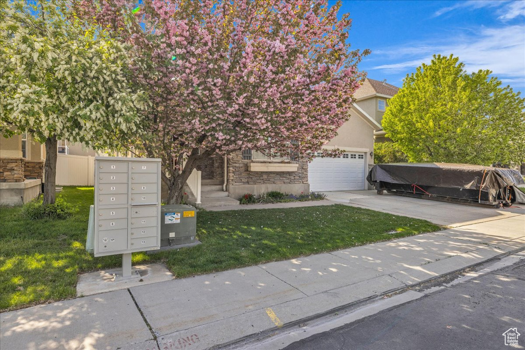 Obstructed view of property with a garage, a front lawn, concrete driveway, and stucco siding